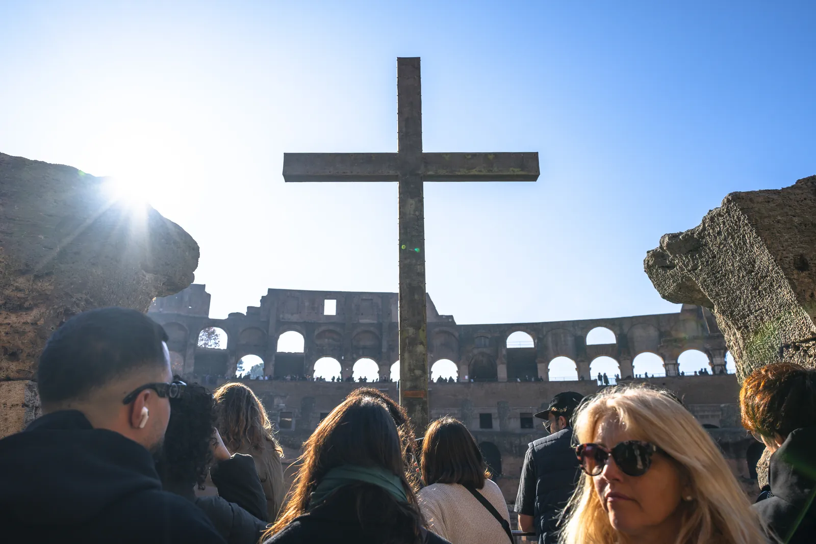 The cross inside the Colosseum, with visitors on a guided tour